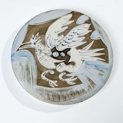 une peinture représentant un oiseau sur une assiette accrochée au mur