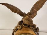 a gold clock with a bird on top of it