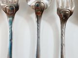 four forks and two spoons on a white surface