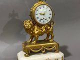 a gold clock sitting on a marble base with a lion on it