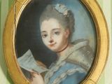 un tableau représentant une femme en train de lire un livre, dans un cadre doré