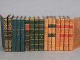 several old books are lined up in a row on a gray surface
