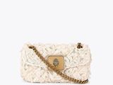 a white handbag with a chain strap and a flower design