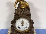 a small clock with a statue on top of it
