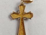 a gold cross pendant on a white background