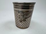 a silver cup with a design on it on a white surface