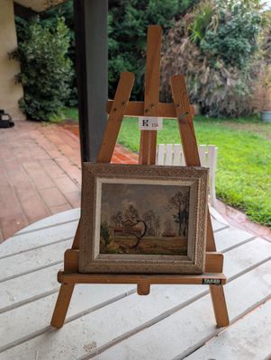 un petit chevalet posé sur une table, sur lequel est posé un tableau