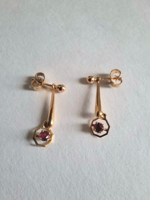a pair of gold earrings with garnets on them