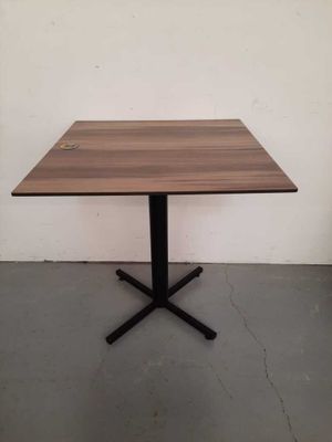 a square wooden table with a black metal cross base
