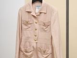 pink jacket hanging on a hanger in front of a beige wall