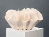 a white sculpture on a white pedestal with a gray background