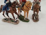 four figurines of men riding on horses in the snow