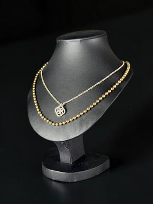 a close up of a necklace on a mannequin on a black background