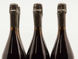 trois bouteilles de vin posées les unes à côté des autres sur une surface blanche