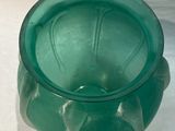 a green glass vase sitting on a white surface