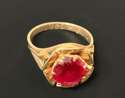 Bague en or sertie d'une pierre rouge.