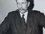 black and white photograph of a man in a suit smoking a cigarette