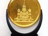 a gold coin sitting on a black stand on a white surface