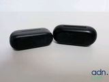 pair of black ear buds sitting on top of a white table