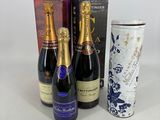 trois bouteilles de champagne et une bouteille de vin posées sur une table