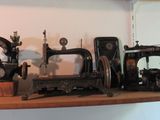 plusieurs machines à coudre anciennes sont posées sur une étagère dans une pièce