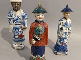 trois figurines représentant des hommes asiatiques debout les uns à côté des autres