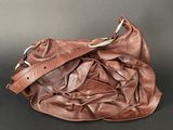 brown leather purse on black background with strap and clasp