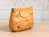 leather handbag on a wooden table in front of a white wall