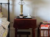 une petite table sur laquelle est posée une lampe, à côté d'un lit