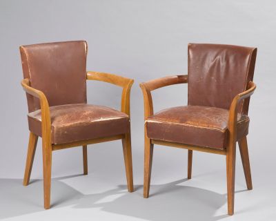 two brown leather chairs sitting next to each other on a gray surface