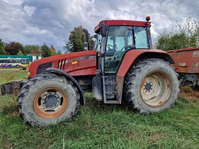 un tracteur rouge garé dans l'herbe