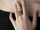 someone is wearing a ring that has a green stone on it