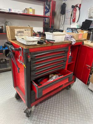 un chariot à outils rouge contenant des outils, dans un garage