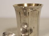 two spoons and a silver cup on a table