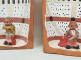 two clay figurines of a man and a woman sitting on a bench