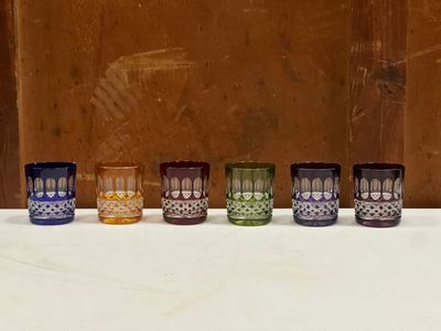 plusieurs verres de différentes couleurs sont alignés sur une surface blanche