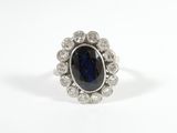 a close up of a ring with a blue stone surrounded by diamonds