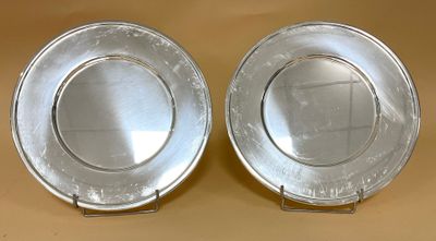 paire d'assiettes argentées sur un socle, sur fond beige clair