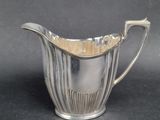 silver plated creamer with a wavy design on the bottom