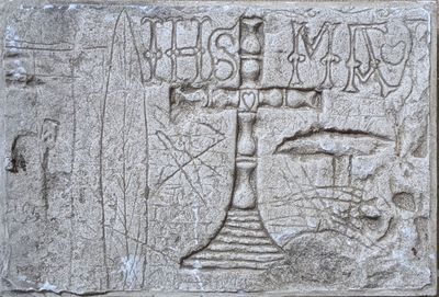 a stone plaque with a cross on it on the side of a building