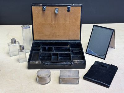 une valise noire avec un miroir, un miroir et d'autres objets posés sur une table