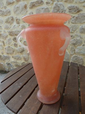 an orange vase sitting on a wooden table near a stone wall