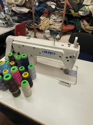 une machine à coudre posée sur une table, avec de nombreuses bobines de fil