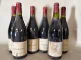 six bottles of red wine are lined up on a counter