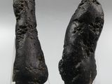 two pieces of black rock sitting on top of a clear stand