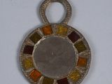 une image représentant un pendentif en verre argenté et multicolore posé sur une surface blanche