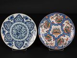 two blue and white plates with floral designs on them on a black surface