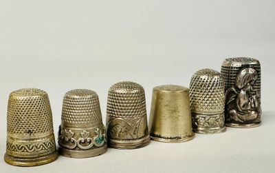 five thimbles lined up in a row on a white surface