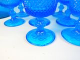 several blue glass goblets sitting on top of a white table
