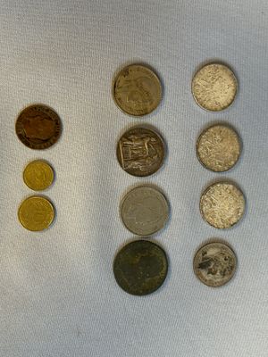 Plusieurs pièces de monnaie différentes sont disposées en rangée sur une surface blanche
